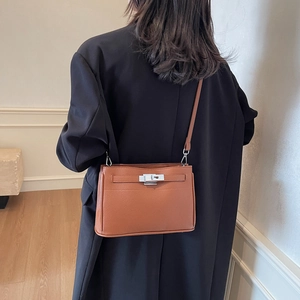 Brown litchi grain leather shoulder bag with silver hardware on a professional model
