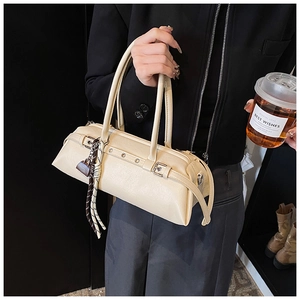 Detail of beige leather baguette bag with silver buckles and decorative metal lock