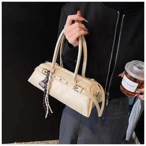Detail view of cream leather baguette bag with silver buckles and woven pendant