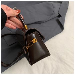 Detail view of dark brown gloss crossbody bag with gold hardware and side hook