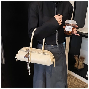Close-up of cream Boston bag with metallic buckle, silk scarf and lock pendant detail