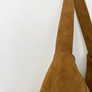 Close-up of durable brown suede fabric and premium stitching on a shoulder bag strap