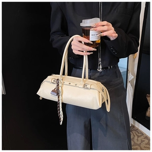 Close-up of cream baguette bag with metal studs and decorative plaid silk scarf