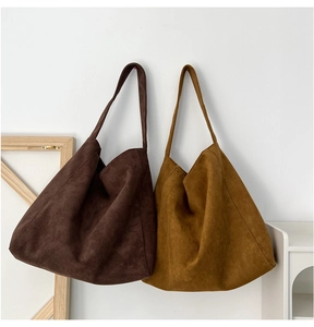 Minimalist large suede hobo shoulder bags in dark brown and ginger yellow on wall display