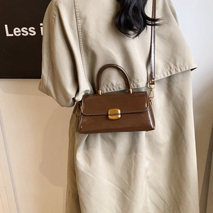 Detail view of retro brown crossbody bag with gold rotating lock on model