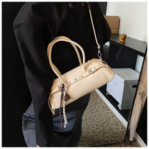 Close-up of beige cylindrical baguette bag featuring eyelet buckles and woven rope detail