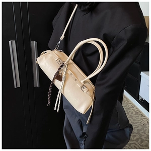Detail view of cream Boston bag with silver buckles and heart-shaped lock charm decoration