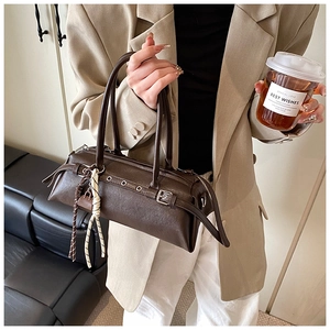Detail of dark brown baguette bag with silver grommets and woven cord strap accents