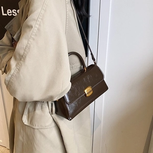 Detailed side view of dark brown oil-wax leather handbag with gold metal clasp
