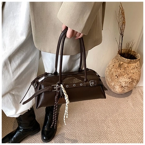 Detail of vintage brown leather boston bag with adjustable side buckles and woven tassel