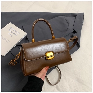 Detail of dark brown leather handbag with glossy texture and gold twist-lock closure