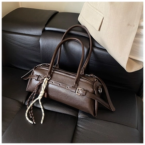 Detail of dark brown baguette bag with dual handles and woven cord ornament