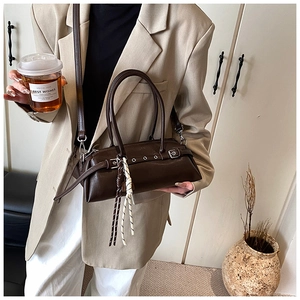 Detail of dark brown leather cylinder bag with vintage buckle and metal eyelets