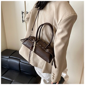 Close-up of a dark brown baguette bag with leather texture and rope tassel detail