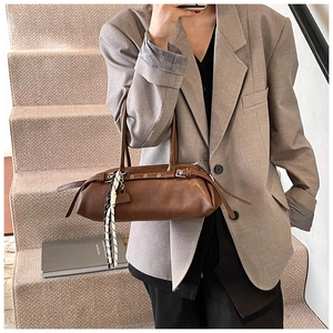 Detail of brown faux leather shoulder bag with decorative scarf on a stylish strap