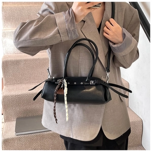 Detail of black leather shoulder bag with metallic eyelets and woven cord charm