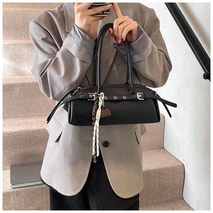 Detailed view of a black leather baguette bag with silver eyelets and silk scarf accent