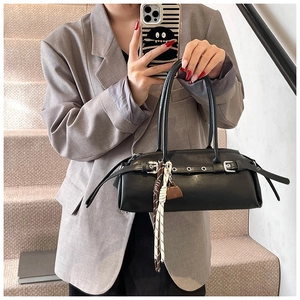 Close-up of black retro baguette bag featuring silver buckles and woven charm detail