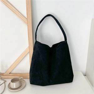 Minimalist black suede tote bag with large capacity displayed in a stylish home setting