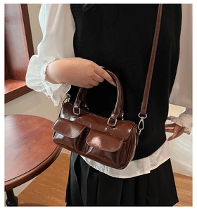 Detail of dark brown vintage bowling bag with front pockets and silver hardware on model