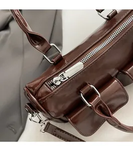 Detail of dark brown leather shoulder bag featuring smooth silver zipper and hardware