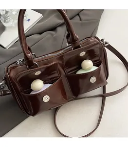 Detail of brown glossy leather handbag featuring front dual pockets and magnetic closures