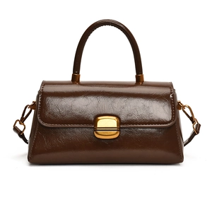 Minimalist dark brown polished leather handbag with elegant gold hardware and top handle