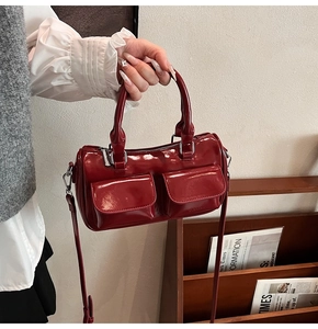 Detail view of red glossy patent leather shoulder bag with front pockets and logo