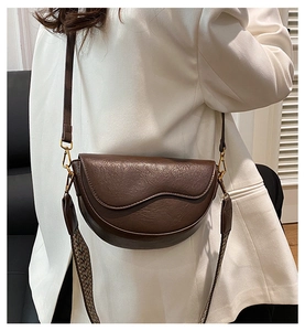 Detail of vintage brown saddle bag with wavy trim and geometric woven strap