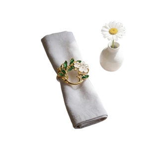 Golden gardenia leaf napkin ring with white flowers on a grey cotton napkin