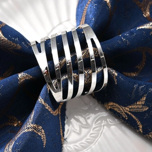 Modern silver diagonal stripe metal napkin ring with spiral hollow design on blue cloth