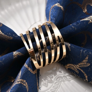 Modern gold spiral metal napkin ring with diagonal stripes on a dark blue cloth