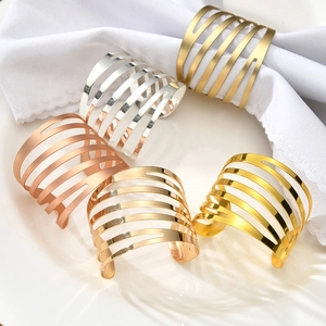 Close-up of five hollow metal napkin rings in gold, silver, and rose gold on a ceramic plate