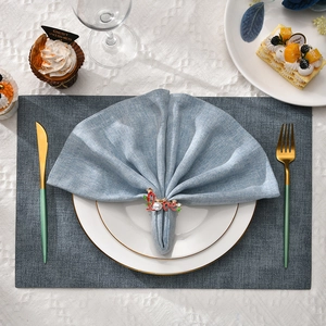 Elegant gold Love napkin ring with red enamel and pearls on a blue linen napkin