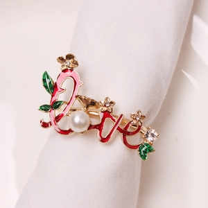 Detail of gold Love napkin ring with rose flower, pearl and rhinestone on fabric