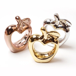 Dettaglio portatovaglioli a forma di mela in oro, argento e oro rosa con cuore scavato
