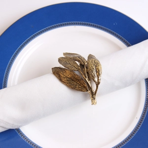 Top view of vintage gold leaf napkin ring on a white napkin over a decorative plate