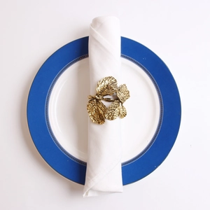 Detailed view of an elegant golden olive branch leaf napkin ring on a white napkin