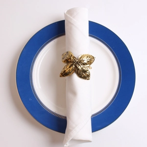 Macro detail of golden olive leaf napkin ring showing textured metal veins and finish