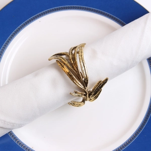 Detail of antique gold olive branch napkin ring with leaf texture on a white cloth