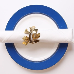 Detailed top view of a gold leaf napkin ring with natural vine texture on a ceramic plate