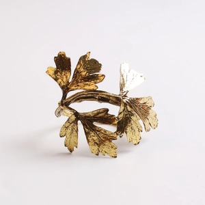Detail of golden olive leaf napkin ring showing realistic leaf vein texture and matte finish