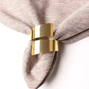 Golden spiral metal napkin ring with polished mirror finish on a grey textured napkin