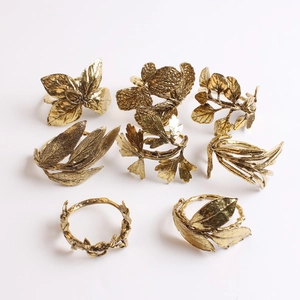 Set of 8 antique gold olive branch and leaf napkin rings on a white background