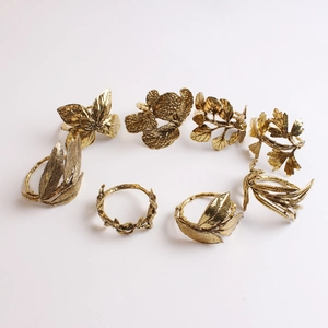Macro shot of 8 vintage golden leaf napkin rings featuring detailed laurel and maple veins
