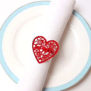 Detail of red heart-shaped LOVE napkin ring with floral vine texture for Valentine's table