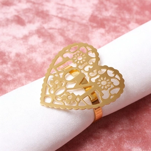 Detail eines goldenen Serviettenrings in Herzform mit LOVE-Gravur auf weißem Stoff