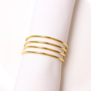 Set of 4 gold minimalist spiral metal napkin rings with polished finish on white fabric