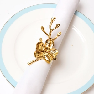 Elegant gold plum blossom napkin ring on white dinnerware for upscale table settings