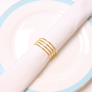 Modern gold spiral metal napkin ring with four-loop coil design on white fabric